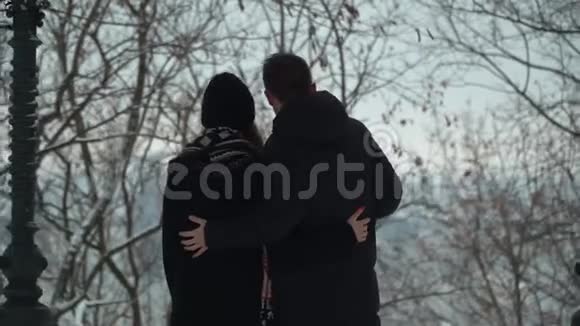 年轻夫妇在冬天的公园里拥抱着雪冬闲的幸福恩爱夫妻年轻日期视频的预览图