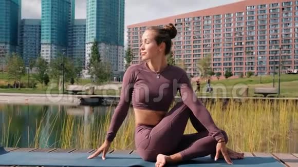 年轻女子做瑜伽运动与城市背景他的姿势阿达马森德拉萨纳视频的预览图