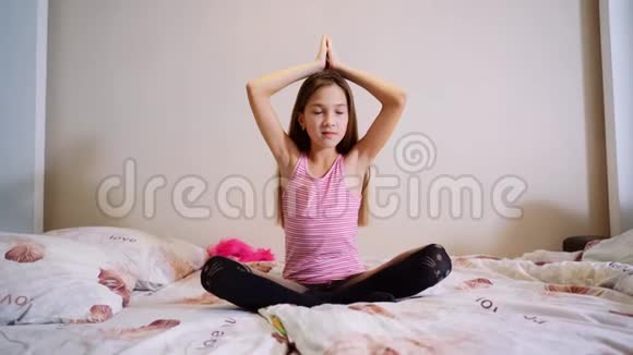 小女孩闭着眼睛双手坐在床上的莲花位置视频的预览图