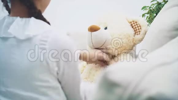 漂亮的女孩重新调整她的泰迪熊的蝴蝶结亲吻她的毛绒朋友把注意力集中在熊身上视频的预览图