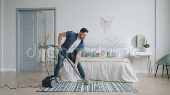 快乐的人用吸尘器和舞蹈缓慢地打扫家里视频的预览图
