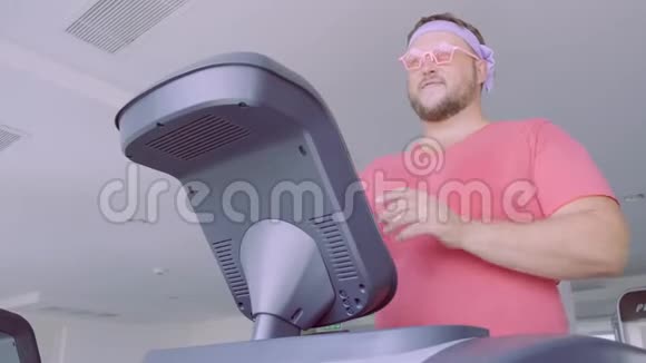 穿着粉红色T恤和粉红色眼镜的花花公子在健身房从事健身活动视频的预览图