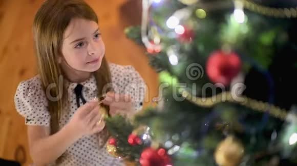 房间里坐在地板上的可爱女孩装饰了一棵带球的圣诞树视频的预览图