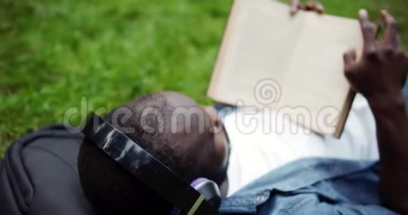 非洲裔美国人拿着书躺在草坪上视频的预览图