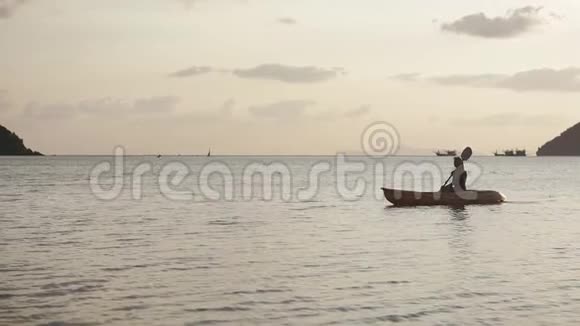 一个手里拿着桨的年轻女子正在皮艇上漂浮视频的预览图