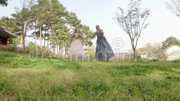 两个年轻活泼的女人穿着传统的韩国服装在公园里跳舞视频的预览图