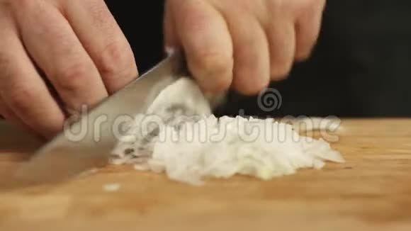用菜刀把白色洋葱切在木制砧板上库存录像准备视频的预览图