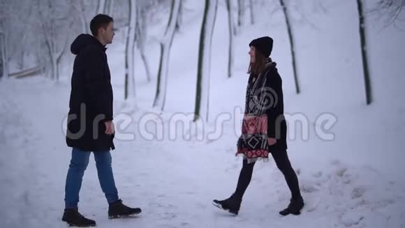 这对年轻夫妇在一个下雪的公园里接吻年轻夫妇的约会户外休闲视频的预览图