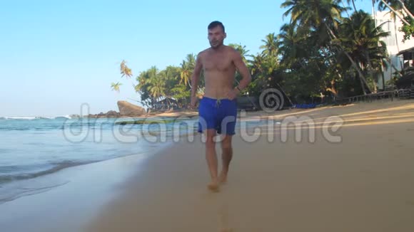 光脚男子沿着平静的海洋海岸线奔跑视频的预览图