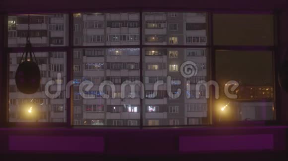 从一个大的空训练馆的窗户到晚上的高住宅楼的视野库存录像城市视频的预览图
