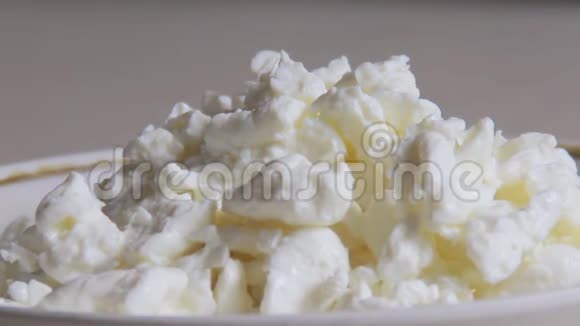 新鲜的颗粒干酪倒在粉红色酸奶上视频的预览图