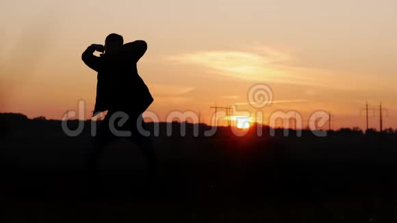 日落时分在田野里疯狂跳舞的男人的剪影视频的预览图