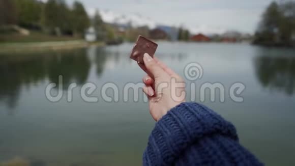 在模糊的自然背景下用女性手合上一块巧克力视频的预览图