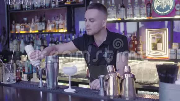 可爱的专业酒吧老板把饮料从量杯倒入金属摇床视频的预览图