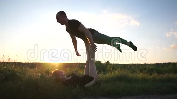 在斯洛莫的日落时分一个运动女孩躺在地上用脚抱着他的男人做麻雀的造型视频的预览图
