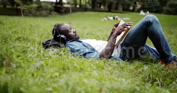 非裔美国人拿着书躺在草坪上视频的预览图
