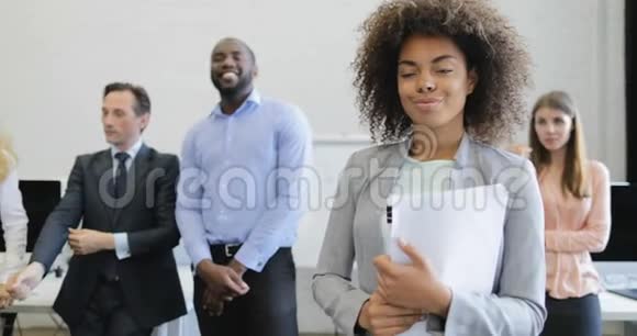 非洲裔美国女商人手持文件微笑着面对商业人士集体集思广益会议现代开放视频的预览图
