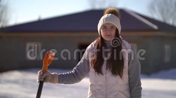 小女孩拿着铲子站在后院雪下后准备清雪的女人视频的预览图