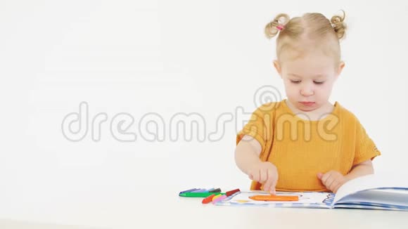 金发婴儿用黄色蜡笔着色未知的图片视频的预览图