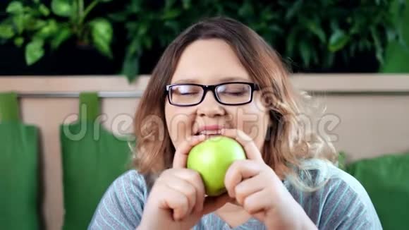 微笑节食胖女人咬鲜青苹果特写镜头视频的预览图