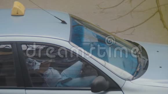 疲惫的出租车司机在停着的车里检查智能手机视频的预览图