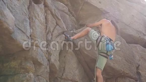 年轻强壮的人攀岩者爬上花岗岩悬崖伸手抓住视频的预览图