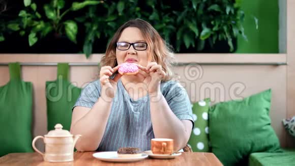 快乐的胖女人咬食欲的甜甜圈有积极的情绪看相机中镜头视频的预览图