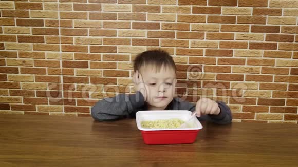 可爱的小男孩在家吃意大利面男孩吃方便面视频的预览图