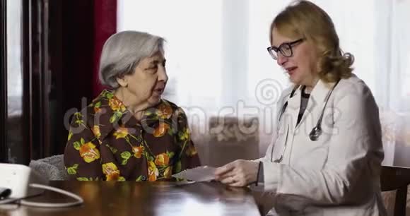 一位皱纹深的老妇人和一位医生谈笑风生视频的预览图