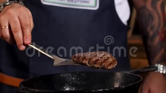 男厨师用铁铲从两边用黑色铁锅煎汉堡肉排的特写镜头股票视频的预览图