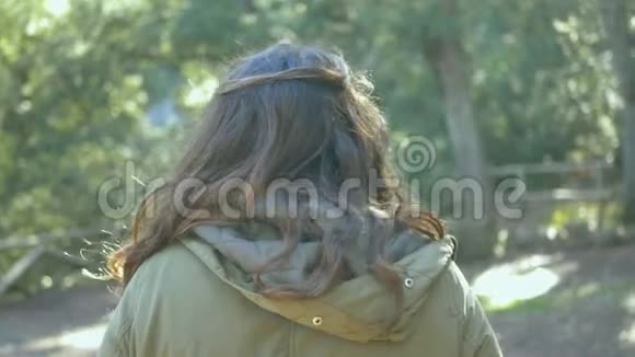 穿绿色夹克的年轻女子穿过森林视频的预览图