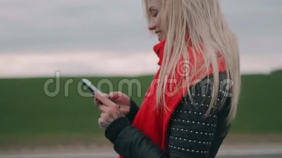 金发女人在路上行走使用智能手机戴着红领巾的女孩看着电话视频的预览图