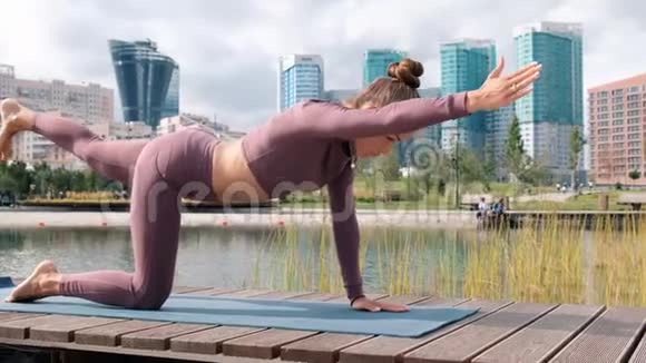 年轻女子做瑜伽运动与城市背景膝盖的平衡姿势视频的预览图