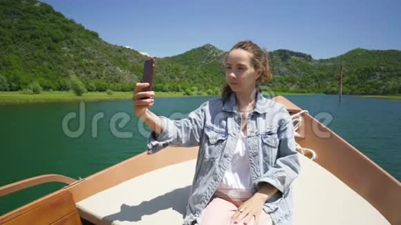 年轻女子坐在摩托艇上打视频电话视频的预览图