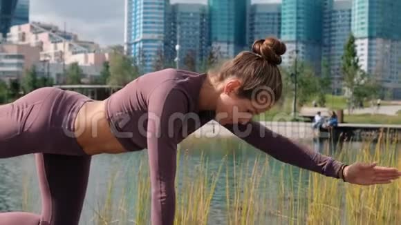 年轻女子做瑜伽运动与城市背景膝盖的平衡姿势视频的预览图
