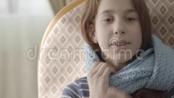 正面可爱的少女从脖子上摘下温暖的蓝色围巾微笑着把它扔了起来视频的预览图