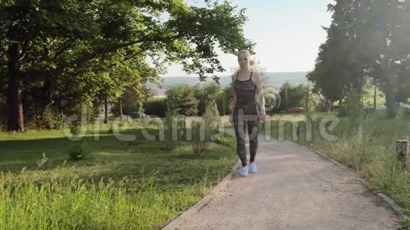 一位身穿卡其布运动服装在公园奔跑的金发女子的正面景色视频的预览图