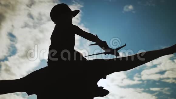 剪影快乐的父亲和小儿子一起在蓝天上玩飞机玩具孩子和他父亲视频的预览图