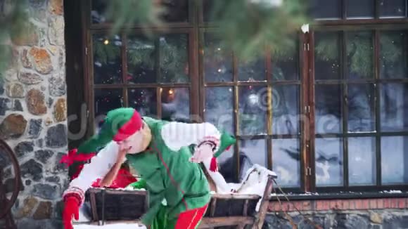 快乐的精灵在雪地里玩耍两个穿着绿色西装的活泼的仙女在户外的大窗户附近在一起玩得很开心视频的预览图
