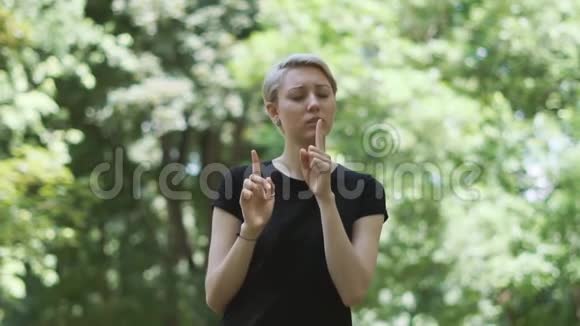 在斯洛莫的一条小巷里一个精神上金发的女人把食指放在嘴唇前视频的预览图