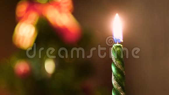 在模糊的彩色圣诞背景上点燃蜡烛概念关上绿色新年蜡烛的火焰视频的预览图