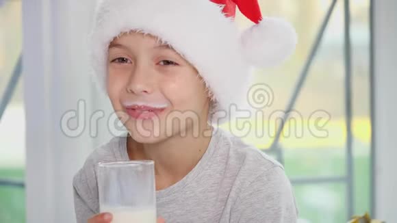 裁剪了4k视频小男孩戴着圣诞帽喝牛奶吃美味的饼干舔牛奶胡子视频的预览图