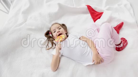 可爱的视频华丽的孩子与有趣的辫子醒来舔红黄色的糖果棒享受这一刻视频的预览图