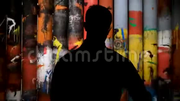 站在彩色笔触覆盖的旋转柱子前的人剪影的后视图现代艺术视频的预览图