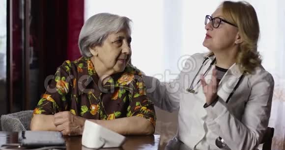 一位皱纹很深的老年妇女和一位年迈的医生看着相机微笑视频的预览图