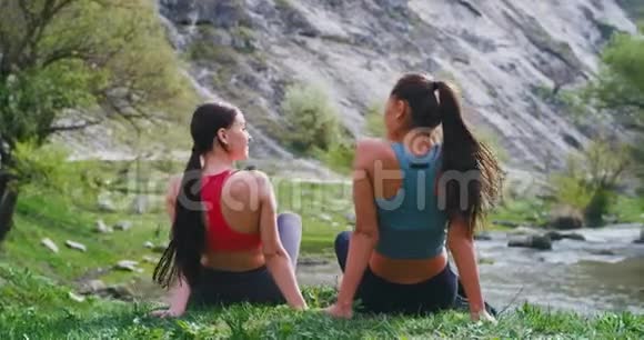 在大自然美丽的地方两位运动的女士在锻炼了一天后享受着时光坐在上面视频的预览图