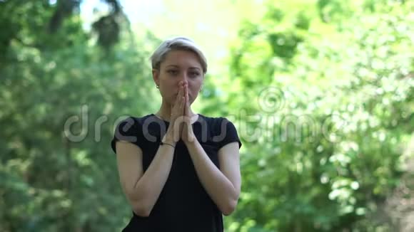 优雅的女人站着双手放在邋遢的木头上祈祷视频的预览图