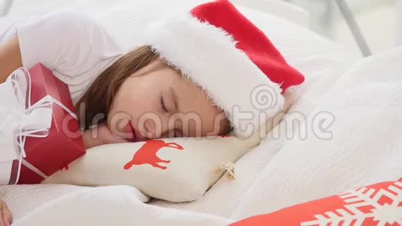 可爱的视频小女孩戴着圣诞帽睡在圣诞礼物视频的预览图