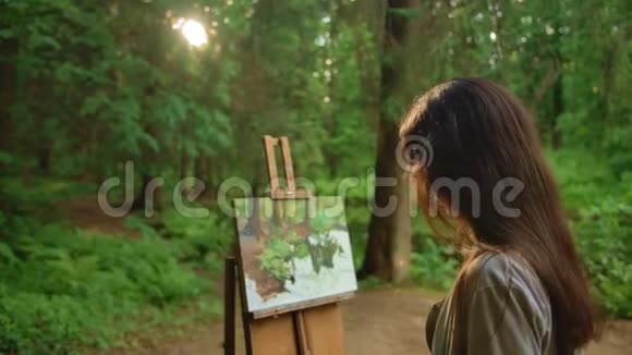 年轻女子在公园里用油画画风景视频的预览图