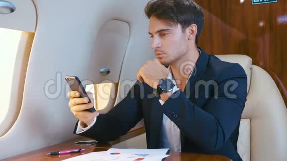 年轻英俊的首席银行家董事商人在飞机上用智能手机飞行成功的商人视频的预览图